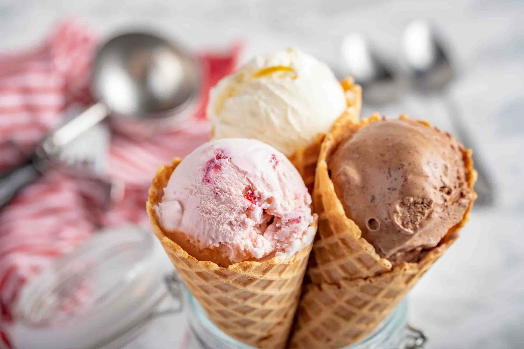 Erdbeer-, Vanille-, Schokoladeneis mit Waffelkegel auf Marmorsteinhintergründen
